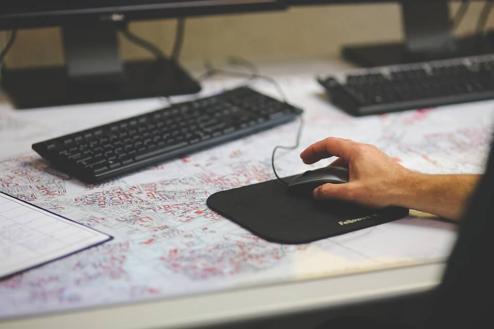 Hand hovering above computer mouse on desk