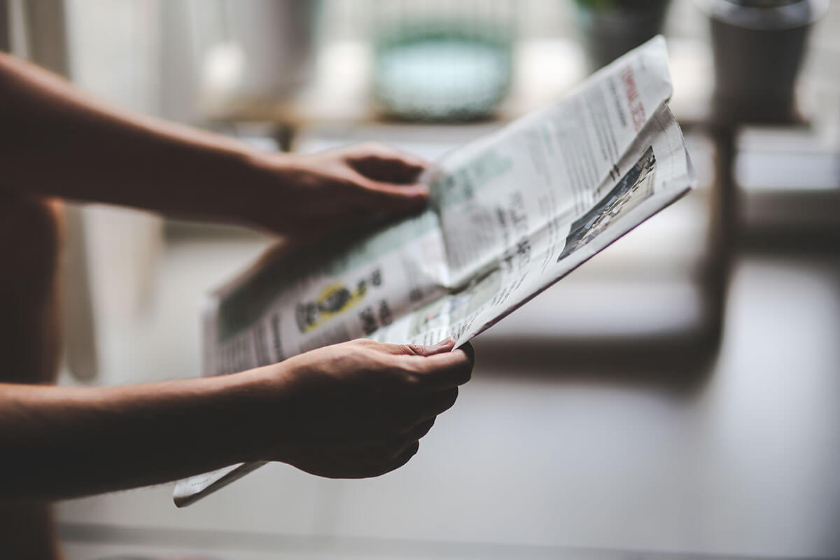 Hands holding open newspaper