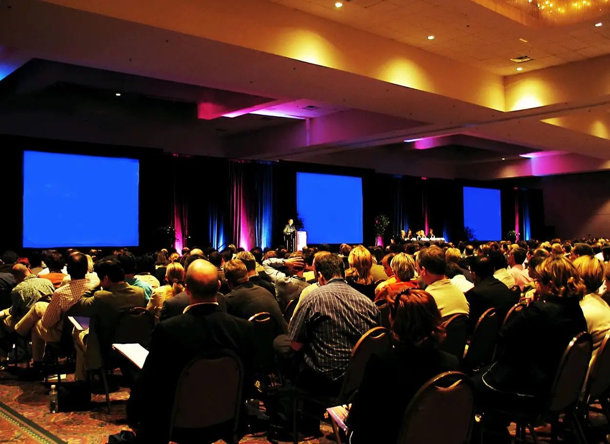Dark, ambient room lit by blue screens at seminar